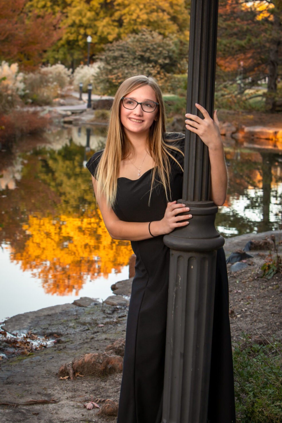 Senior girl posing with light pole for senior portraits in Eastborough Park in Eastborough, KS