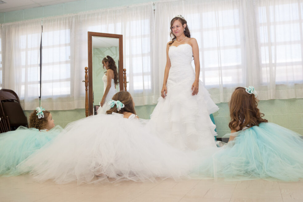 Flower girls look up at bride while getting ready