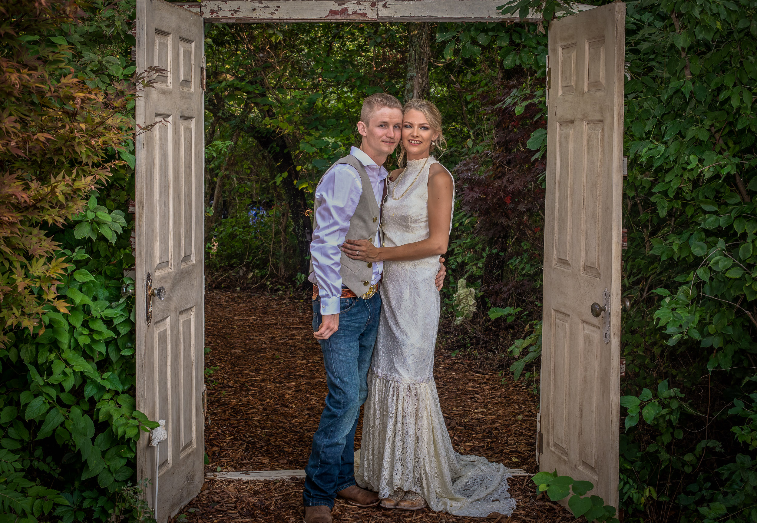 Bride and groom posing in front of the rustic doors at The Red Bud Party Barn Venue in Douglass, KS